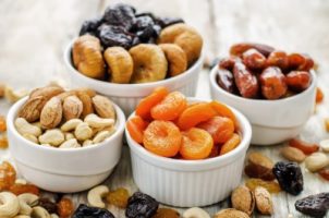 mix of dried fruits and nuts on a white wood background. tinting. selective focus
